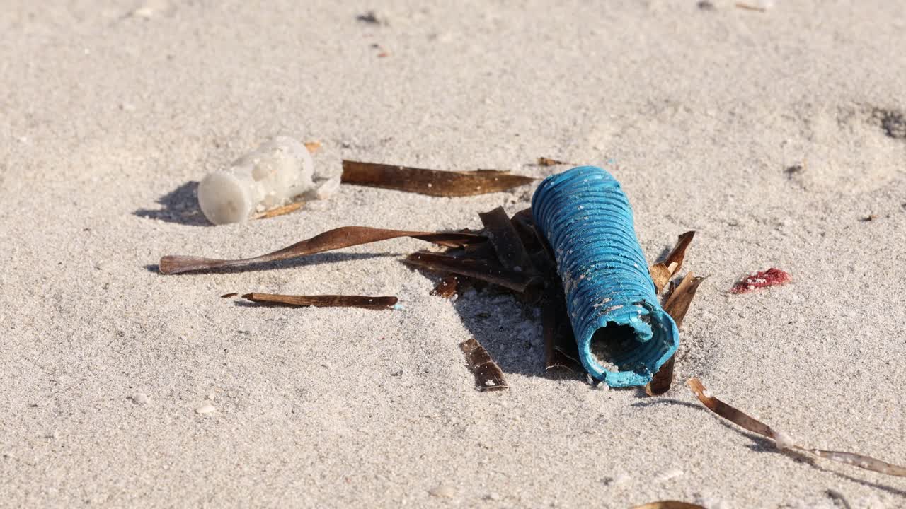 primer plano de un objeto de plástico azul desechado en una playa de arena, concepto de contaminación ambiental