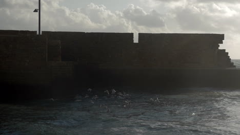 Paisaje-Acuático-Con-Gaviotas,-Mar-Ondulado-Y-Antigua-Muralla-De-La-Ciudad.