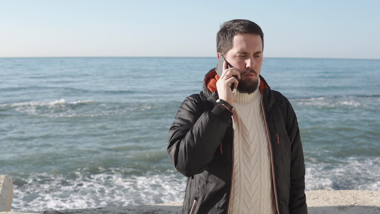 해변에서 전화로 얘기하는 남자
