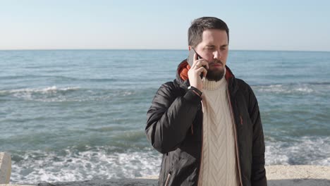 man talking on phone at the beach