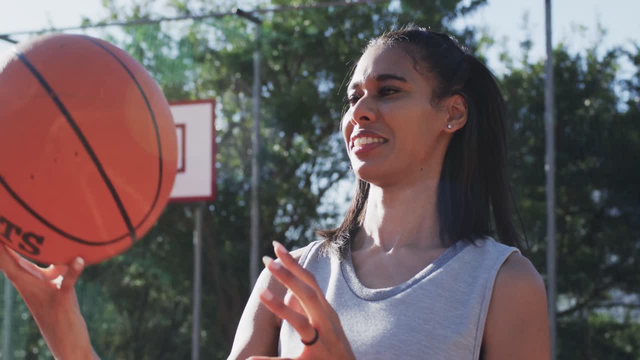 retrato de una jugadora de baloncesto afroamericana girando la pelota en una cancha soleada, en cámara lenta