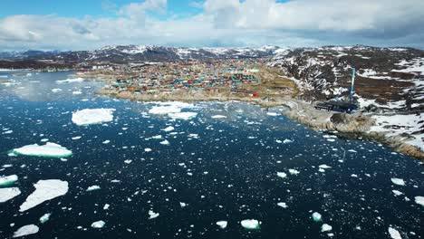 Mountain-landscape-with-small-town-on-coastline-of-Greenland,-aerial-view