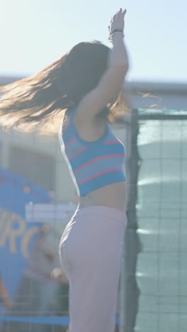 a young woman dancing energetically outdoors in sunlight