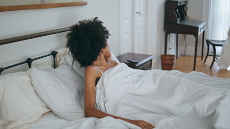 Niña-Somnolienta-Despertando-En-La-Cama.-Señora-Africana-Tomando-Teléfono-Móvil-Tendido-En-El-Colchón