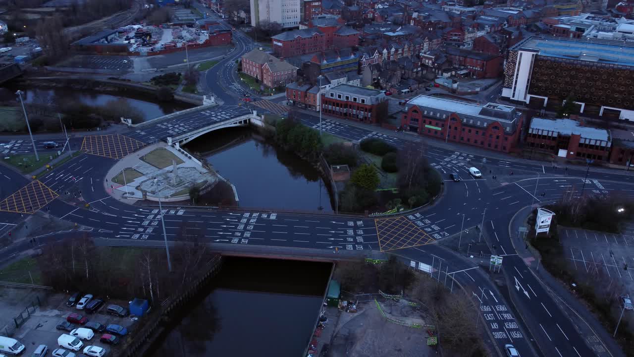 Aerial view looking down city centre canal roundabout infrastructure suburban streets traffic at daybreak right orbit