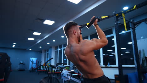 handsome athlete trains with ropes in gym. modern equipment in training hall. selective focus. slow motion.