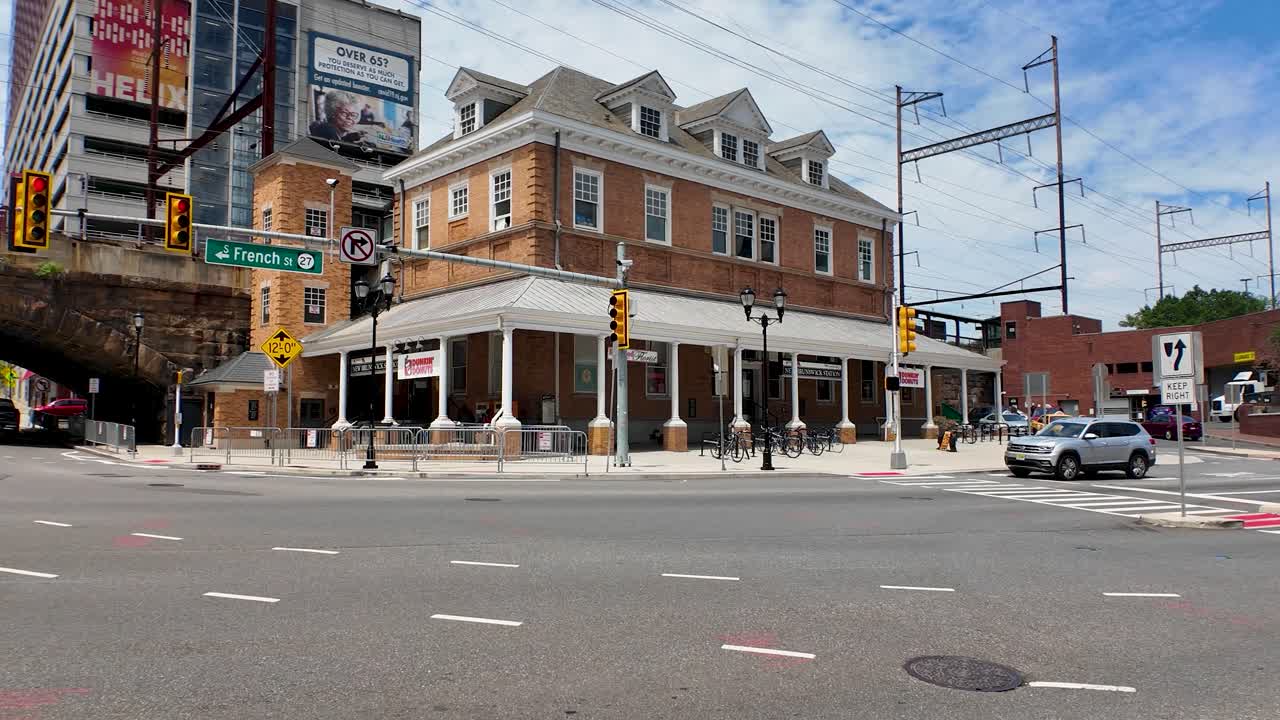 Street view of a prominent brick building housing a Dunkin' at an urban intersection