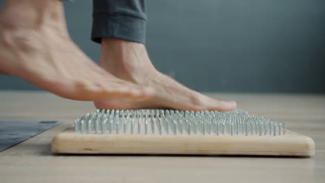 foot reflexology on wooden nail board