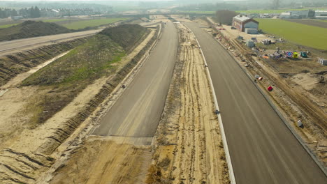 vista aérea de una carretera en construcción con pilas de tierra y maquinaria