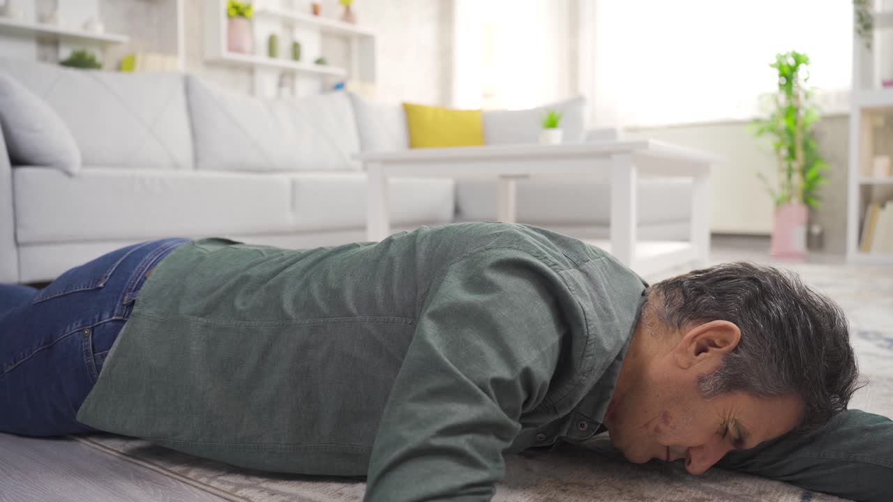 un hombre maduro se desmaya en casa y se derrumba al suelo.