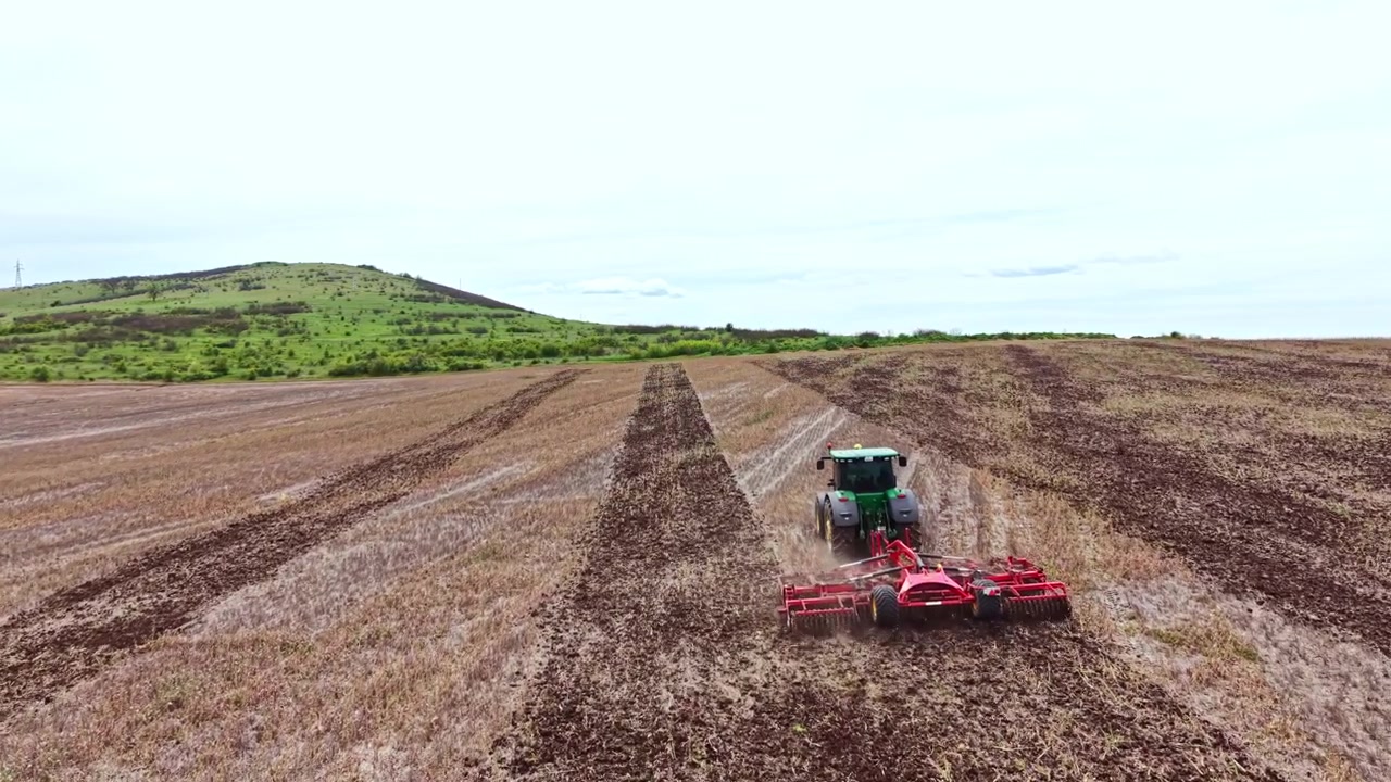 Attrezzature agricole che lavorano in un campo per preparare il terreno per la semina in una zona rurale di giorno in primavera