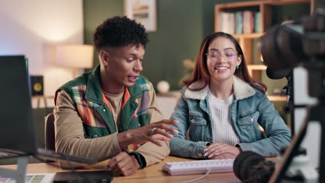 two people at a desk indoors with a camera