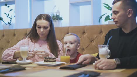 young woman puts cake near boy and takes metal spoon