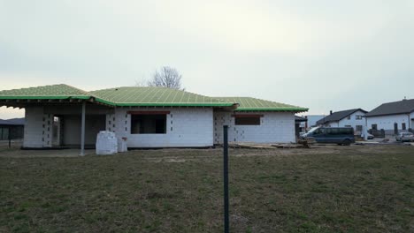 Shot-of-empty-building-under-construction-with-with-parked-truck-in-the-yard-and-houses-in-the-background