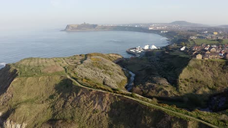 Aerial-tracking-view-showing-sea-and-cliffs,-coastal-town-of-Scarborough-England-UK