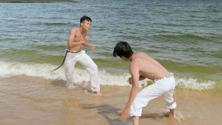 Two men dancing capoeira on the beach