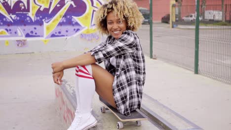 mujer joven de moda sentada en una patineta