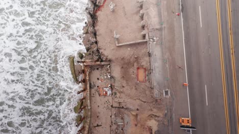 aerial bird's eye shot flying over burned oceanfront residential lots on the pacific coast highway after the palisades wildfire in malibu, california. 4k