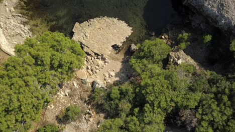 Vista-Aérea-De-Pájaros-De-Un-Pequeño-Lago-Rodeado-De-árboles-Y-Ruinas-Antiguas