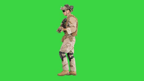 armed man in camouflage with a gun walking on a green screen, chroma key