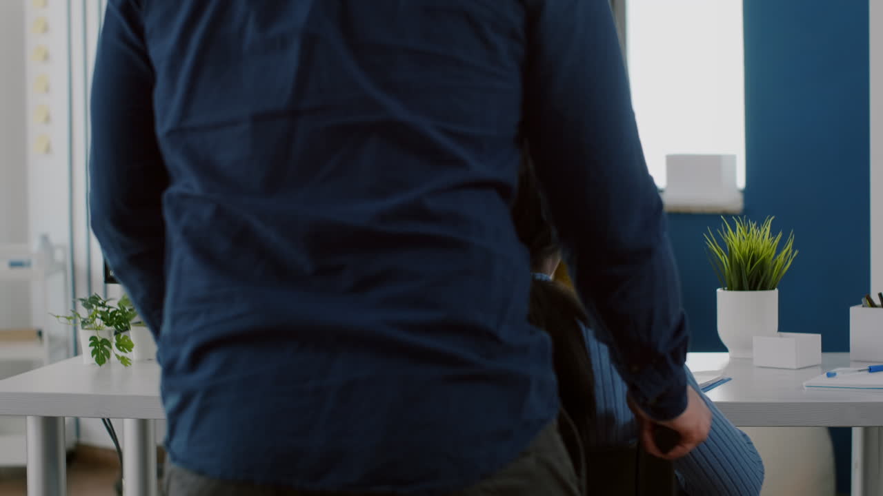 남성 직원이 사무실에 들어오는 흑인 동료를 돕고 있습니다.