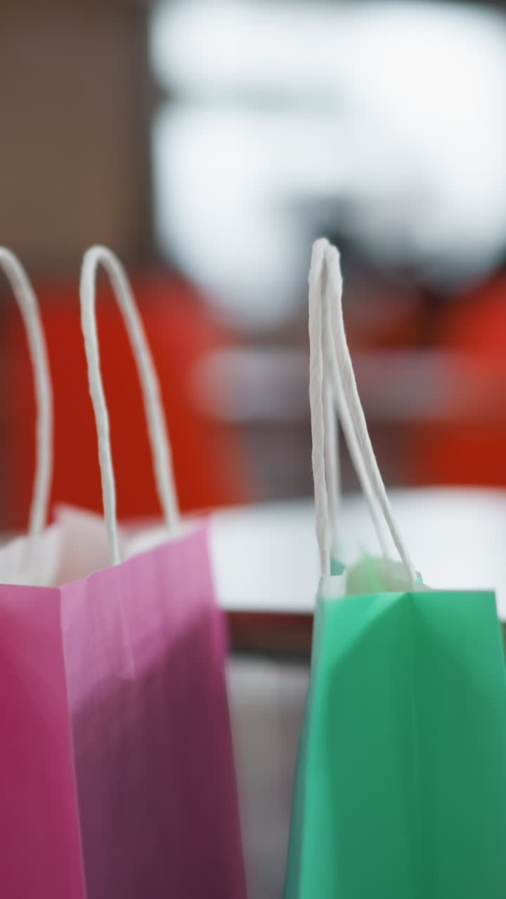 primer plano de bolsas de compras coloridas en la mesa con fondo borroso del centro comercial, iluminación suave que ilumina la escena, ideal para conceptos de compras, ocio, consumismo y estilo de vida del centro comercial