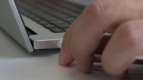 Hand-plugging-white-USB-C-charging-cable-into-laptop,-close-up