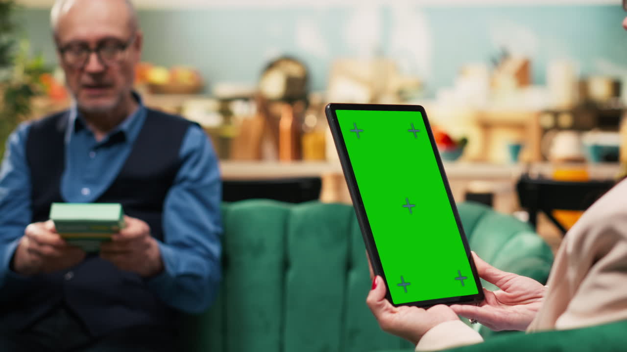 Vertical green screen, tablet device, senior woman and man, relaxing at home