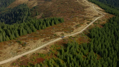 Car-driving-through-mountain-road-among-green-tree-forest