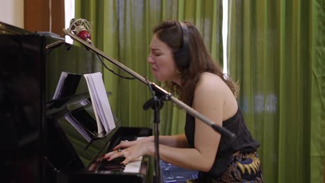 woman playing piano and singing in a recording studio