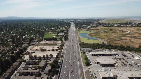 Aerial-view-of-pine-trees-cars-freeway-101-suburbs-dense-trees-rooftop-housesmarsh-electric-transformers-move-forward