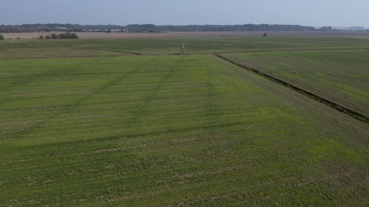 vista aérea volando sobre un mirador de caza de madera en los vastos campos agrícolas de cresnjevec rural, eslovenia