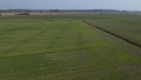 Vista-Aérea-Volando-Sobre-Un-Mirador-De-Caza-De-Madera-En-Los-Vastos-Campos-Agrícolas-De-Cresnjevec-Rural,-Eslovenia