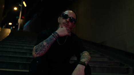 stylish man seated on stairs at night