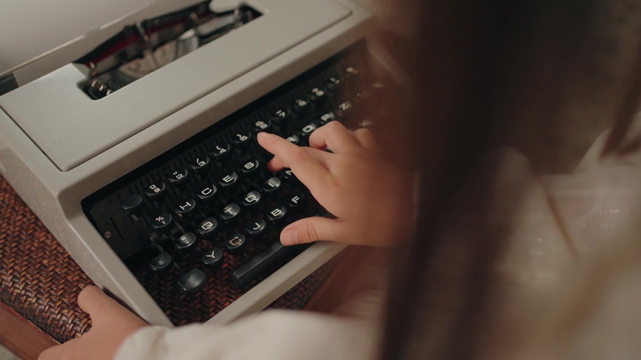 Finger presses typewriter key with both hands steadying it, invoking nostalgia - slow mo