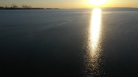 drone shot with tranquil ocean waters, sunlight reflection and row of sailboats