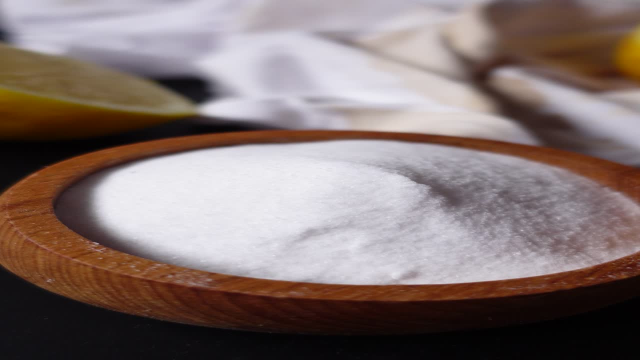 bicarbonato de sodio en un tazón de madera con limones y paños