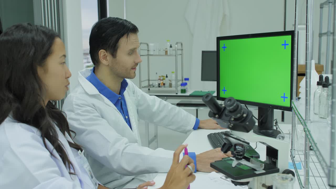dos científicos de investigación médica mirando la pantalla verde en el laboratorio moderno