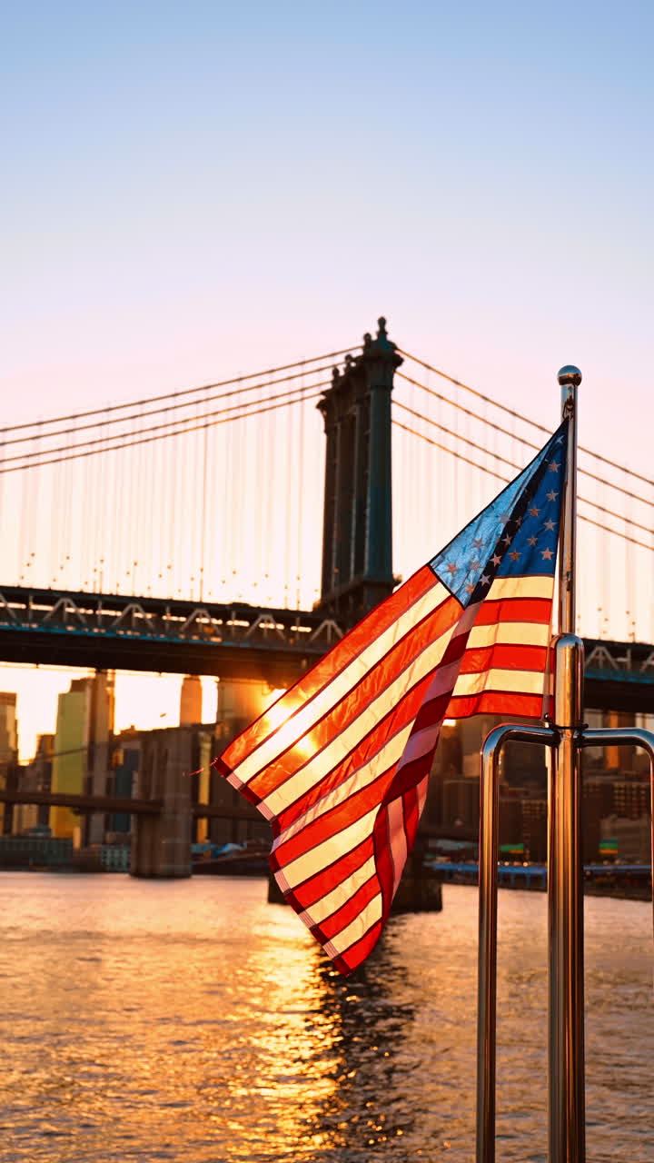 Bandiera americana che sventola delicatamente al vento. Sole al tramonto tra gli edifici e il Manhattan Bridge sullo sfondo. Video verticale
