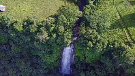 toma aérea vista de pájaro de la hermosa cascada soleada que se inclina hacia arriba revelando un gran campo, meseta de chorcha, chiriquí, panamá