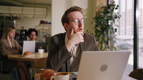 a man is working on his laptop in a coffee shop