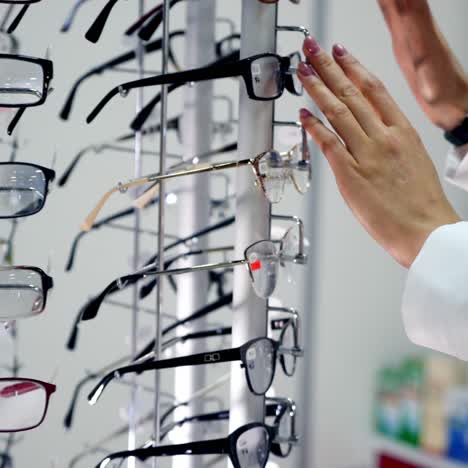 eyesight concept. woman standing near the stand with stylish eyeglasses in the optical store. buyer choosing new glasses in the shop.