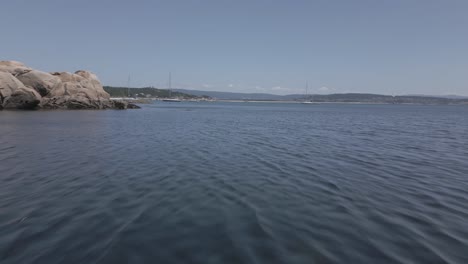 Raw-Aerial-Footage-of-Clear-Water-Ocean-with-Sailboats-and-Land-in-Horizon