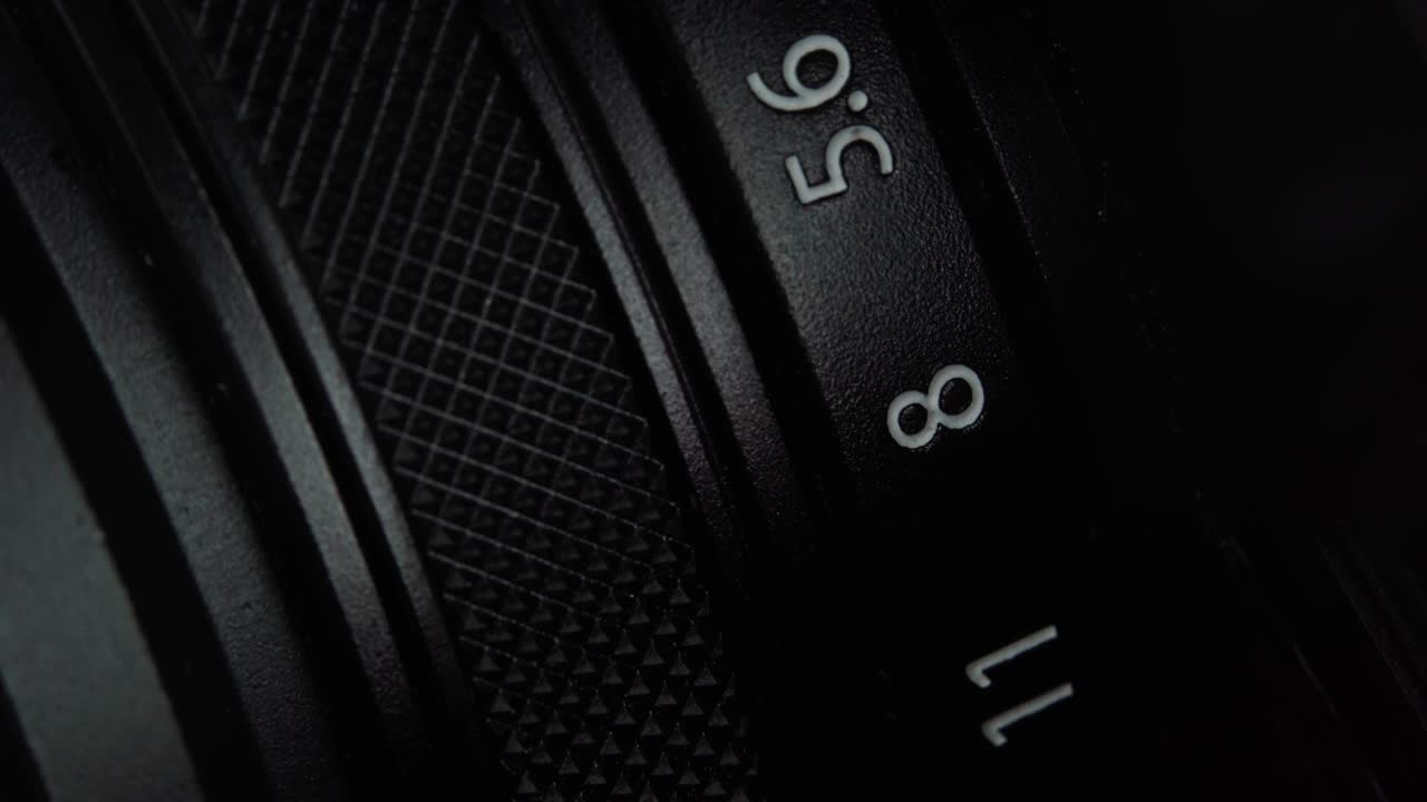 Macro view of rotation mirrorless or DSLR camera aperture ring. Changing the focus setting on old looking camera. Extremely detailed close up. Professional vintage photography equipment.