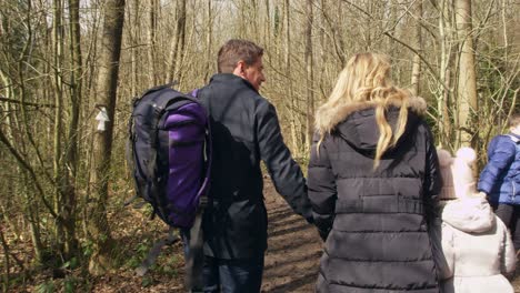 family of four and pet dog walking through forest, handheld, shot on r3d