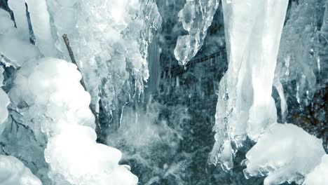 slow motion closeup of small ice waterfall caused by icy stream