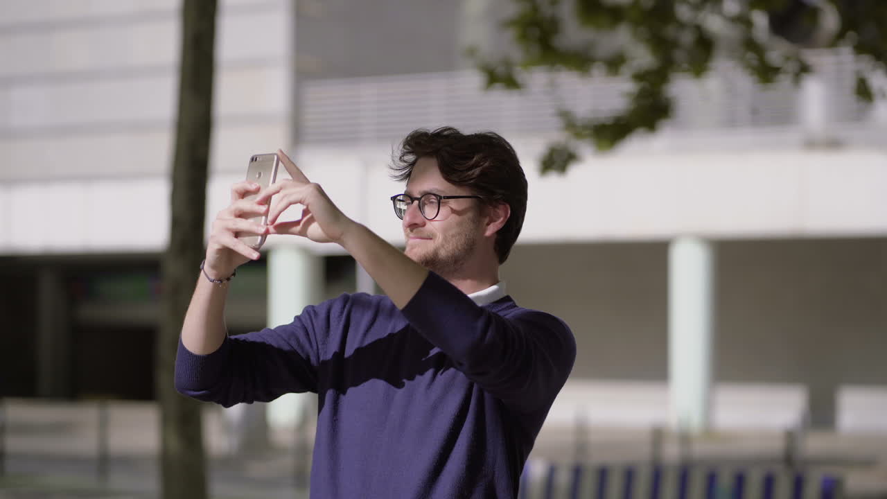 hombre con gafas usando un teléfono inteligente en la calle