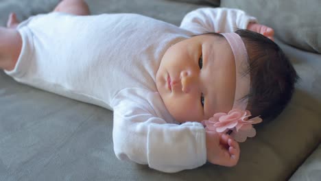 a newborn baby lays quietly on a couch