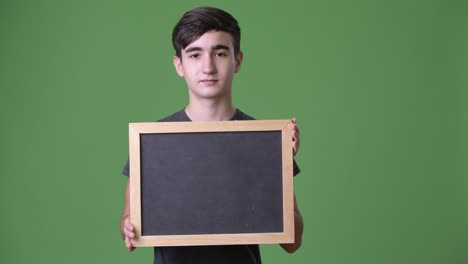 young handsome iranian teenage boy against green background