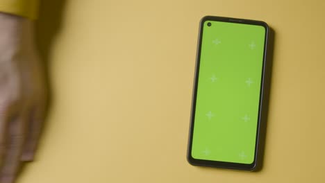 Studio-Overhead-Shot-Of-Plastic-Numbers-Arranged-In-Order-With-Green-Screen-Mobile-Phone-On-Yellow-Background-2